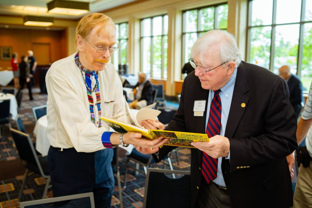 President Emeritus Don Lubbers looking at a book with a guest at the Retiree Reception.